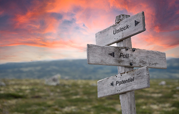 wooden signpost with directions to unlock full potential against a colorful sky emphasizing personal growth and journey